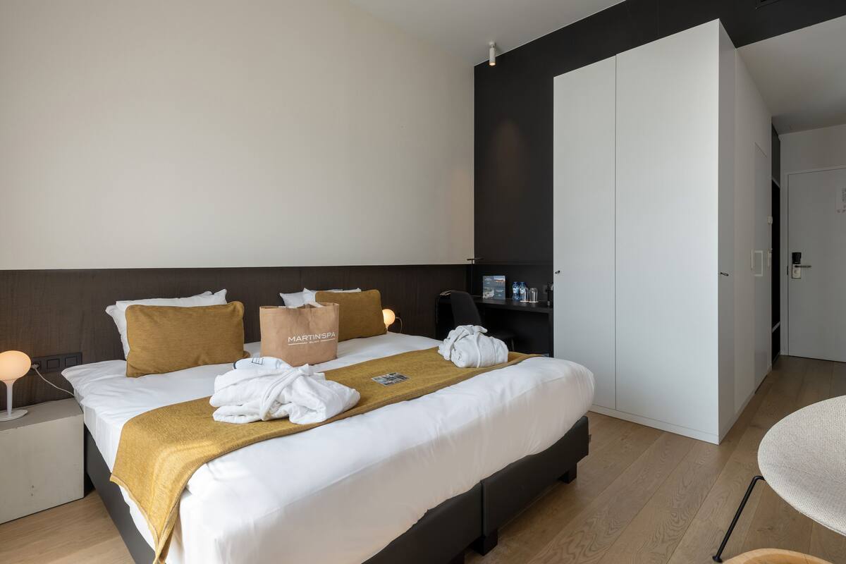 Une chambre d’hôtel comprenant un lit, une table de chevet, un bureau, une chaise, une armoire et une porte.
