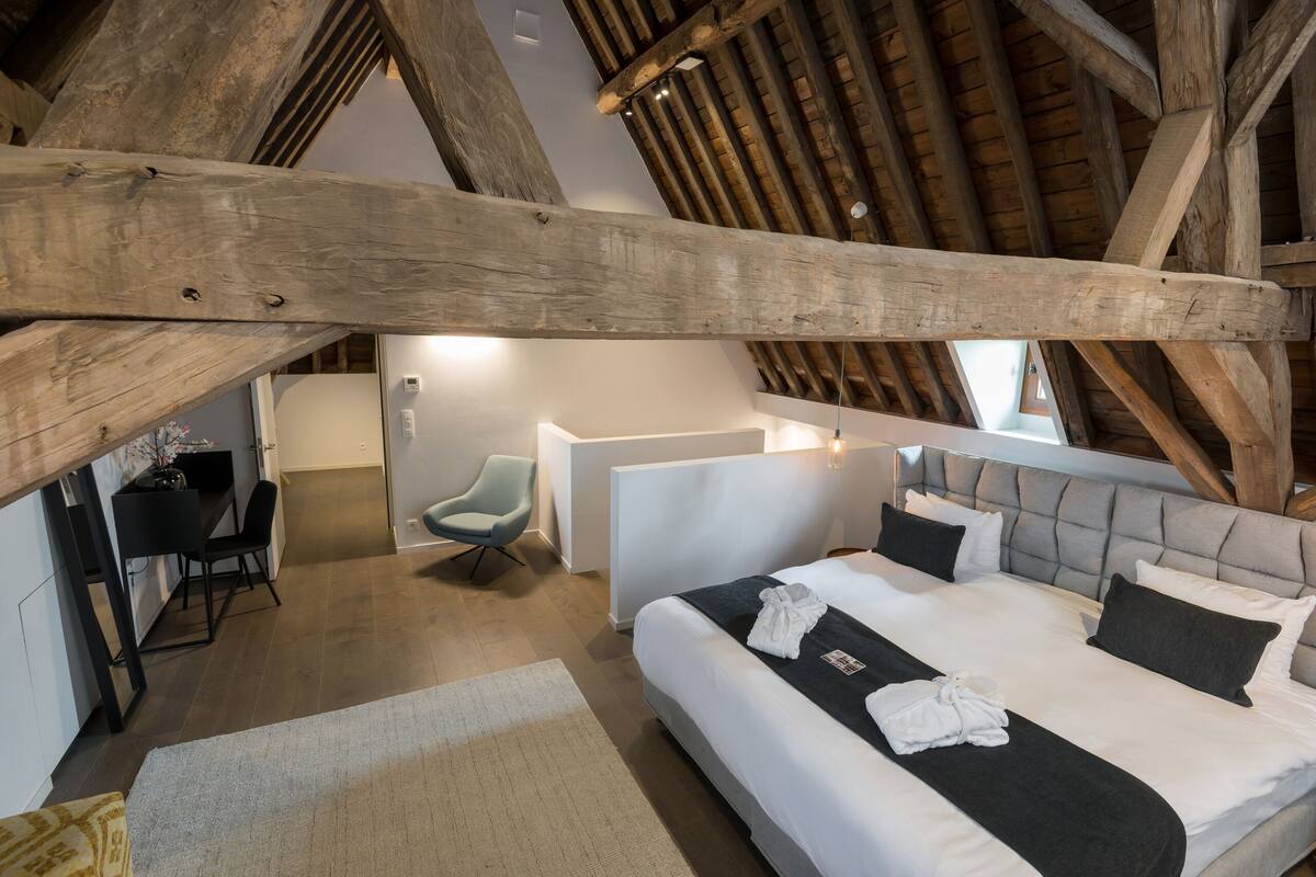 Une chambre d’hôtel avec un grand lit, un bureau, une chaise et une salle de bain moderne.