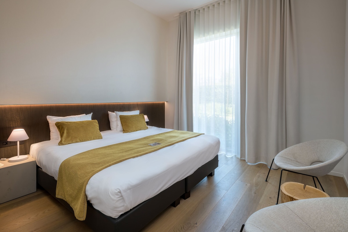 Een moderne hotelkamer met een groot bed, een bedlamp en een stoel.