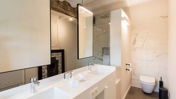 Een moderne badkamer met een dubbele wastafel, een grote spiegel, een toilet en een douche.