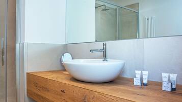 A modern bathroom with a wooden vanity, a white sink, and a large mirror.