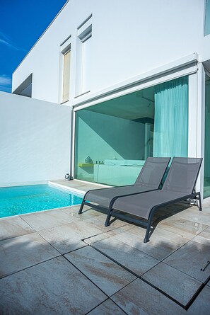 A modern outdoor pool area with a lounge chair, clear blue pool, and a glass-enclosed patio. - Case d'Amare 1 (Jesolo)