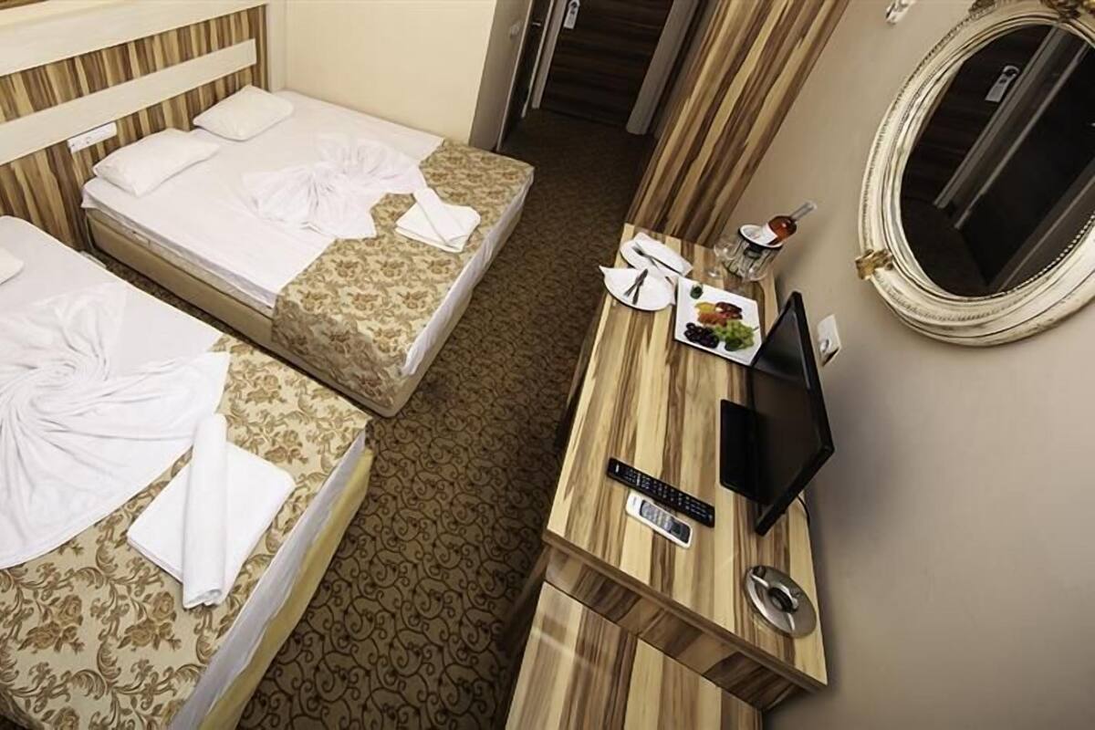 A hotel room with two beds, a wooden dresser with a TV, and a mirror.