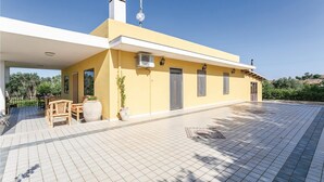 A yellow building with a covered patio, outdoor furniture, and a tiled floor. - Villa Betty (Ragusa -RG-)