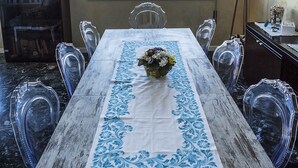 A dining area with a table set for four, a chandelier, and a view of the beach through a window. - Helvezia (Jesolo)
