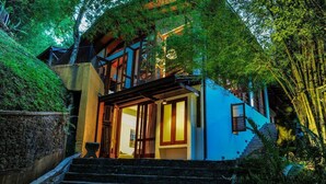 Una casa moderna con fachada azul, una escalera de madera y un balcón.