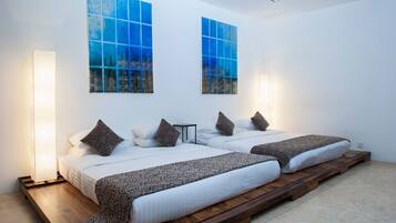 A modern bedroom with two beds, a large window, and a wall-mounted artwork.
