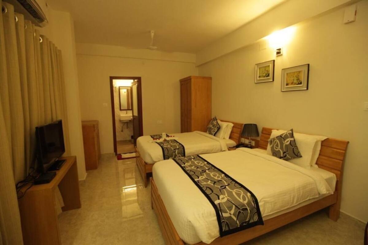 Una habitación de hotel con dos camas, televisión, armario y espejo.