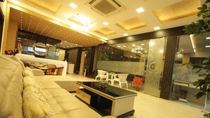 A modern living room with a sofa, a coffee table, and a dining area with chairs. - Grand Cascade (Chennai)