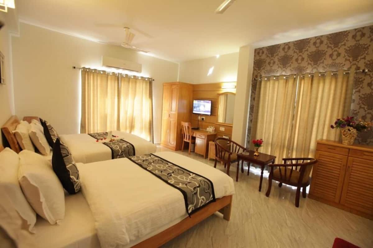 Habitación de hotel con dos camas, un escritorio, televisor y zona de estar.