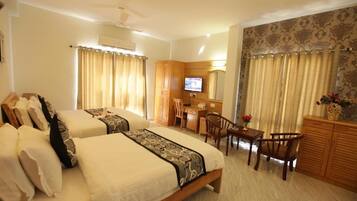 Quarto de hotel com duas camas, uma escrivaninha, televisão e área de estar.