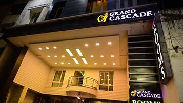 Exterior do Grand Cascade Rooms, com design moderno, varanda e letreiros iluminados.