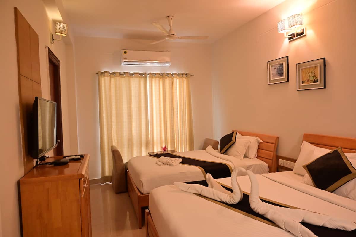 Habitación de hotel con dos camas, televisión, aire acondicionado, ventilador de techo y ventana con cortinas.