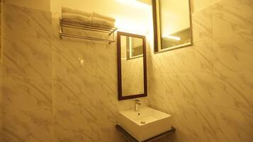 A bathroom with marble walls, a white sink, a towel rack, and a mirror.