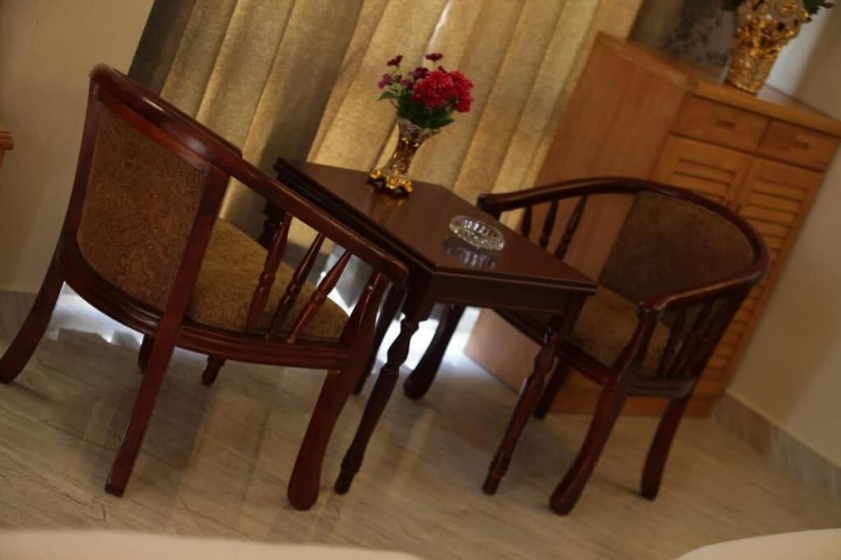Un comedor con una mesa y sillas de madera, un florero con flores y un armario.