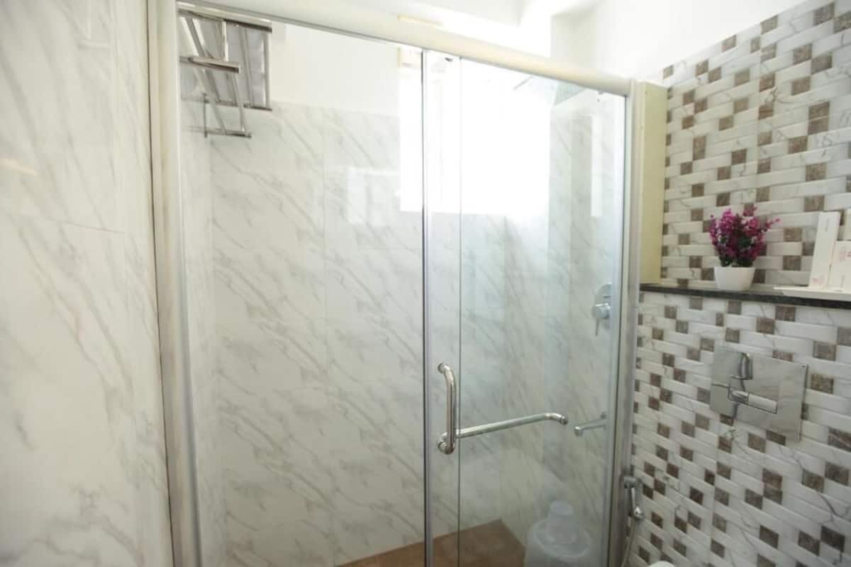 Un baño con cabina de ducha de vidrio, pared de mármol y salpicadero de azulejos.