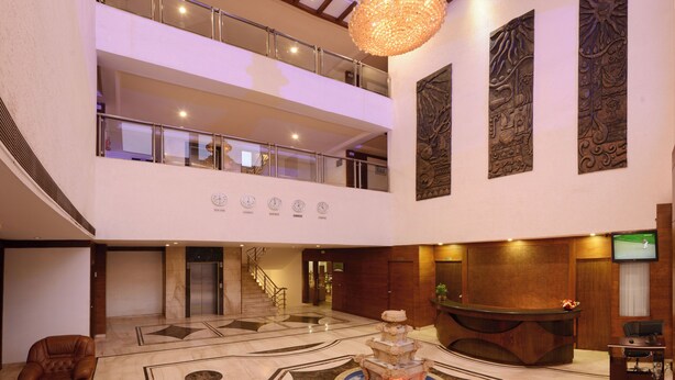 A lobby with a marble floor, a reception desk, a staircase, and a chandelier.