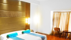 Habitació d'hotel amb un llit gran, una tauleta de nit, una làmpada, una cadira i una taula petita.