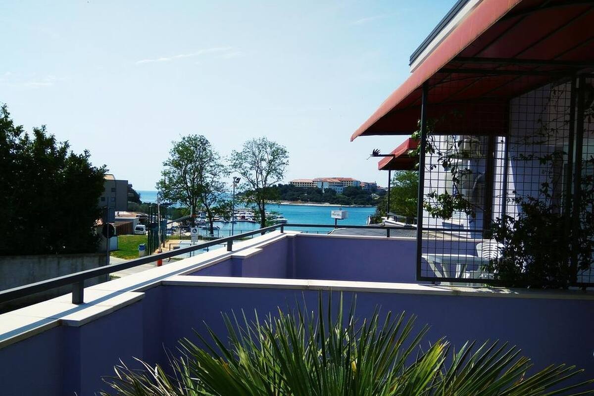 Un balcón con vista a un puerto deportivo y edificios a lo lejos.