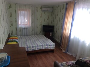 A room with a bed, a TV, and a window with curtains.