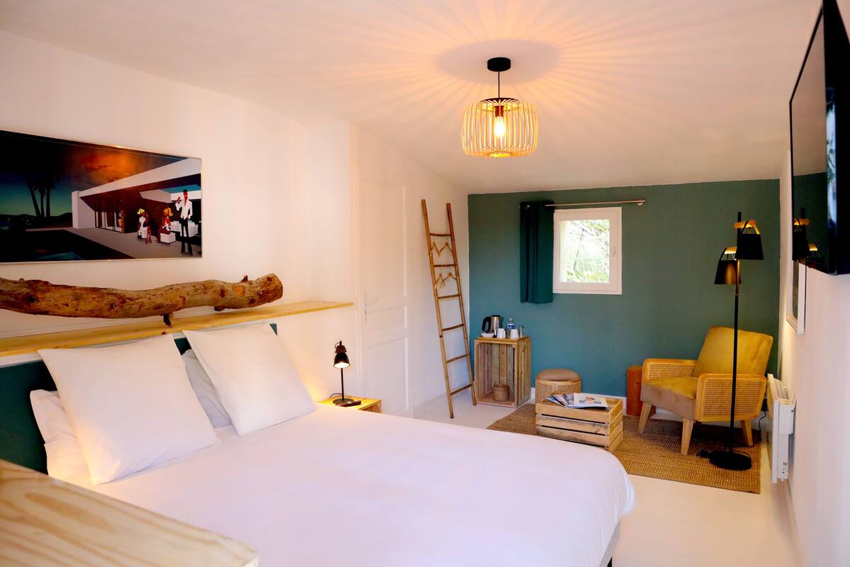Une chambre d’hôtel avec un lit, un tableau, une échelle, une chaise et une lampe.