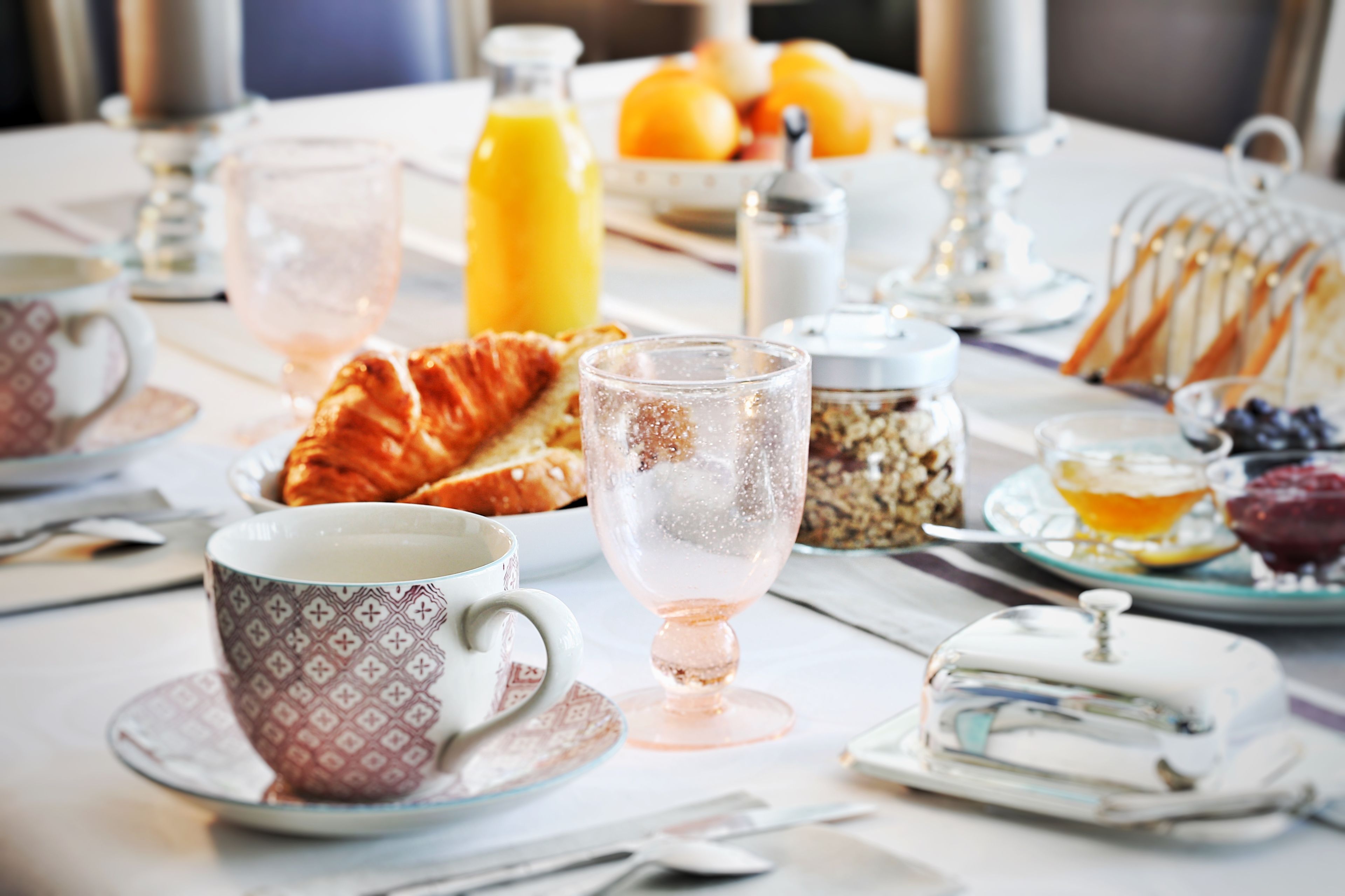 A breakfast table with croissants, a glass of juice, and a cup of coffee.