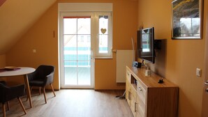 Une pièce comprenant une table à manger, des chaises, un téléviseur et un radiateur.