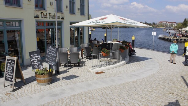 Un café situé au bord de l’eau, avec une terrasse et vue sur le plan d’eau.
