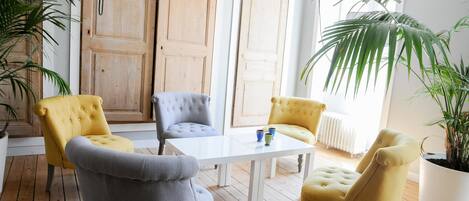 A room with a white table, four chairs, and two large wooden doors.