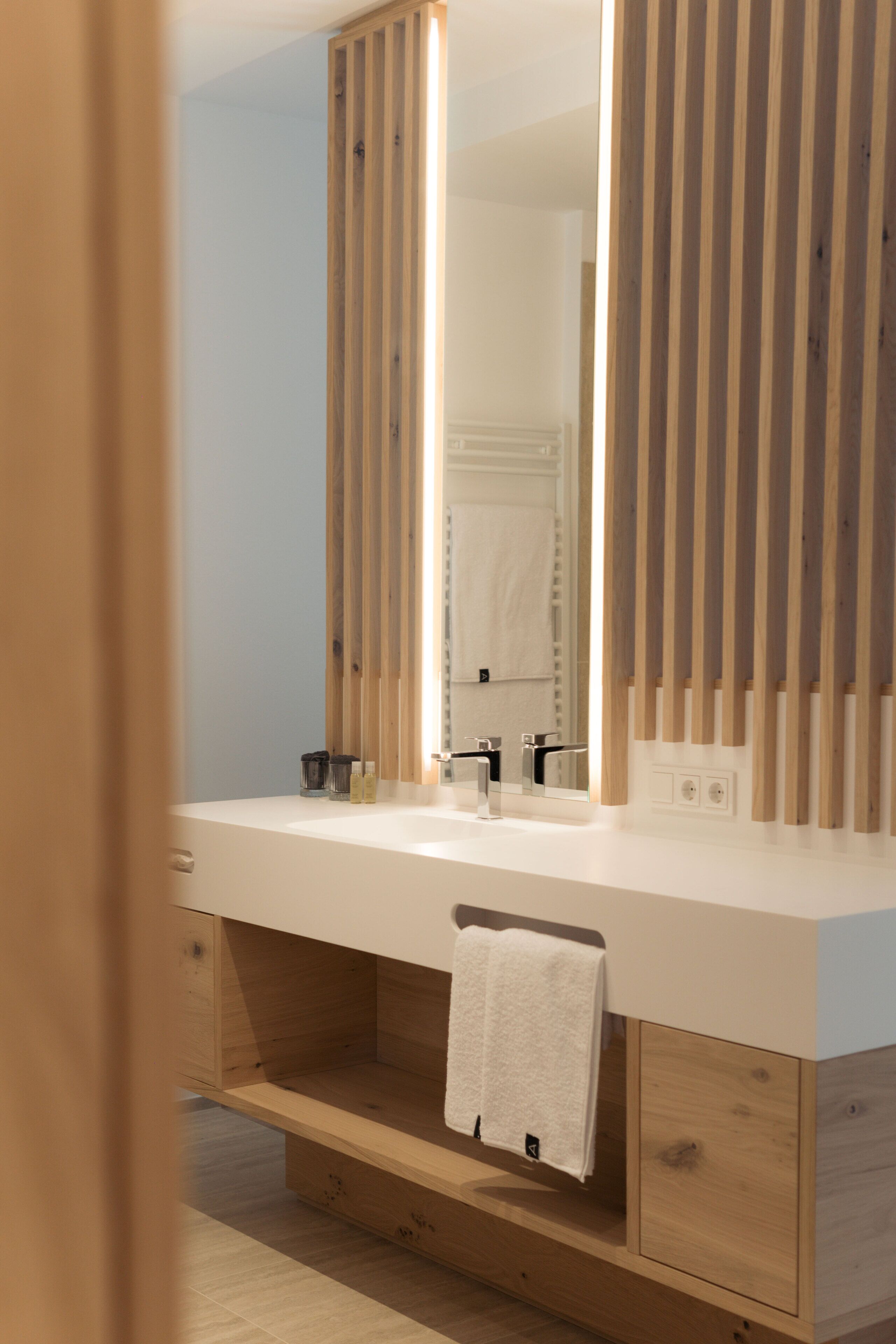 Un bagno moderno con un mobile bagno in legno, uno specchio grande e un asciugamano appeso al lavabo.