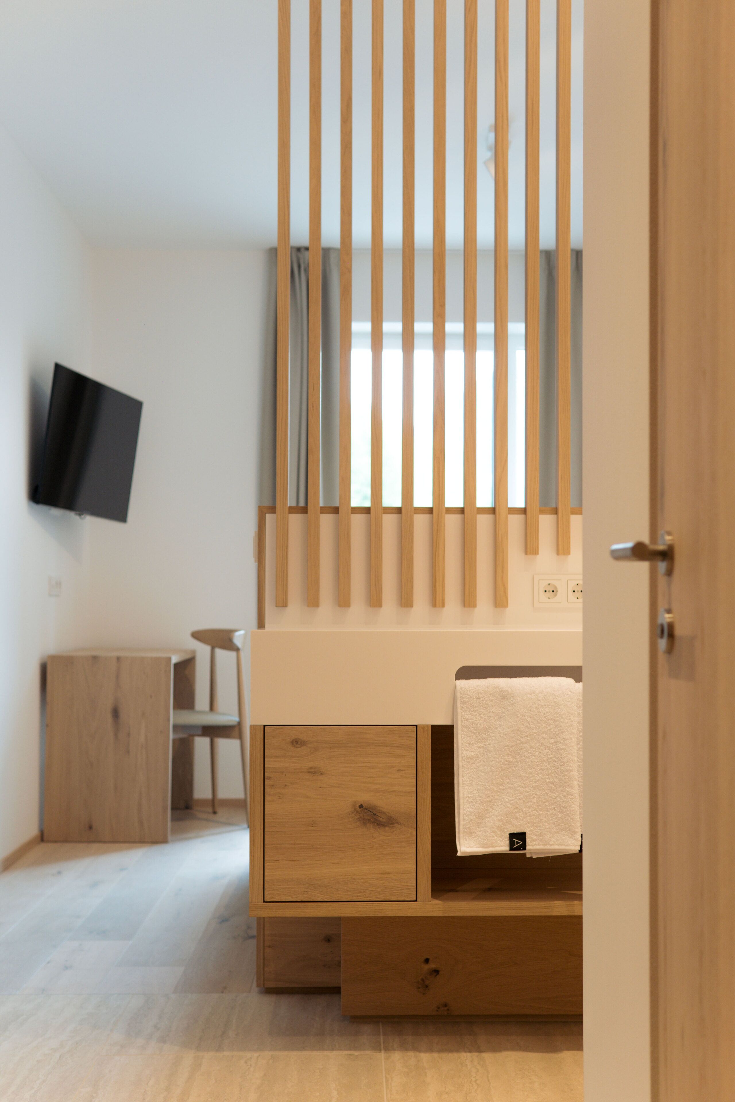 A modern bedroom with a wooden bed, a TV mounted on the wall, and a wooden nightstand.