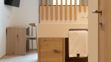 A modern bedroom with a wooden bed, a TV mounted on the wall, and a wooden nightstand.