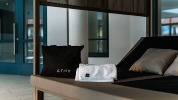 Een moderne hotelkamer met een bed, een zwart kussen, een witte handdoek en een kleine witte tas op het bed.