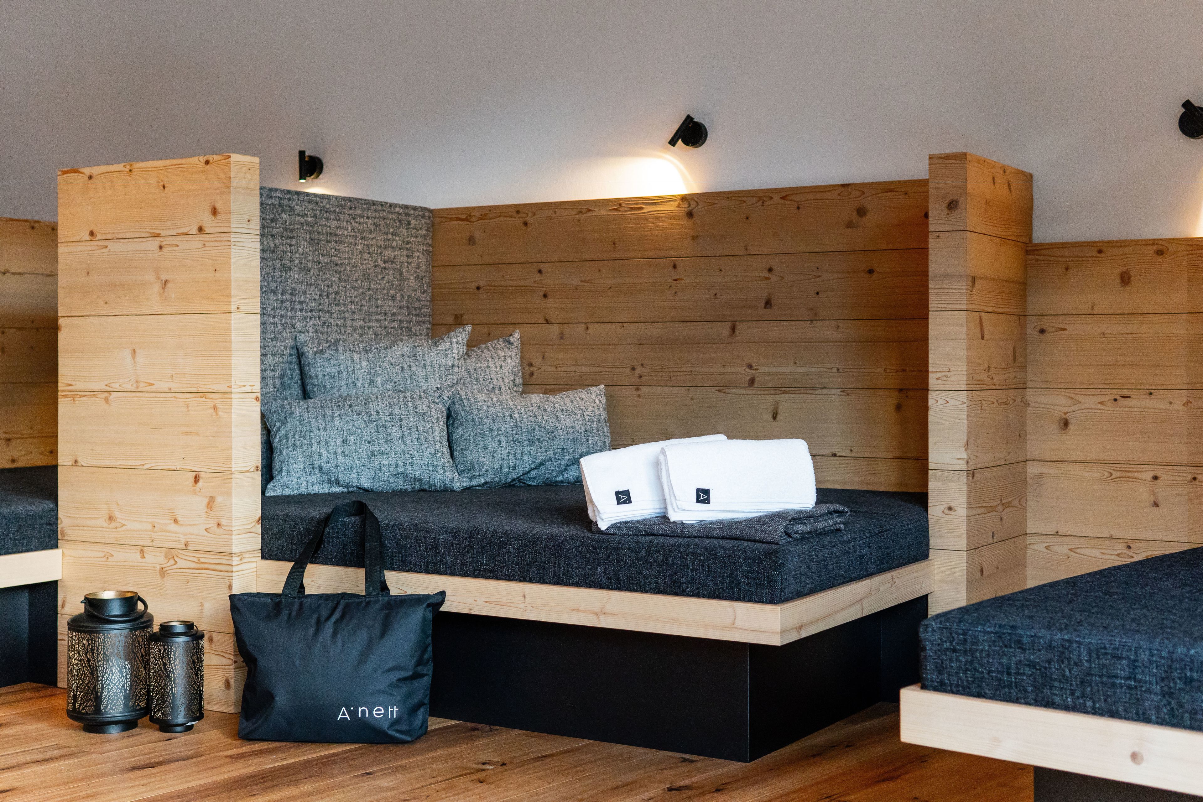 Una habitación moderna con paredes de madera, un sofá gris, un bolso negro y una mesita con dos tazas.