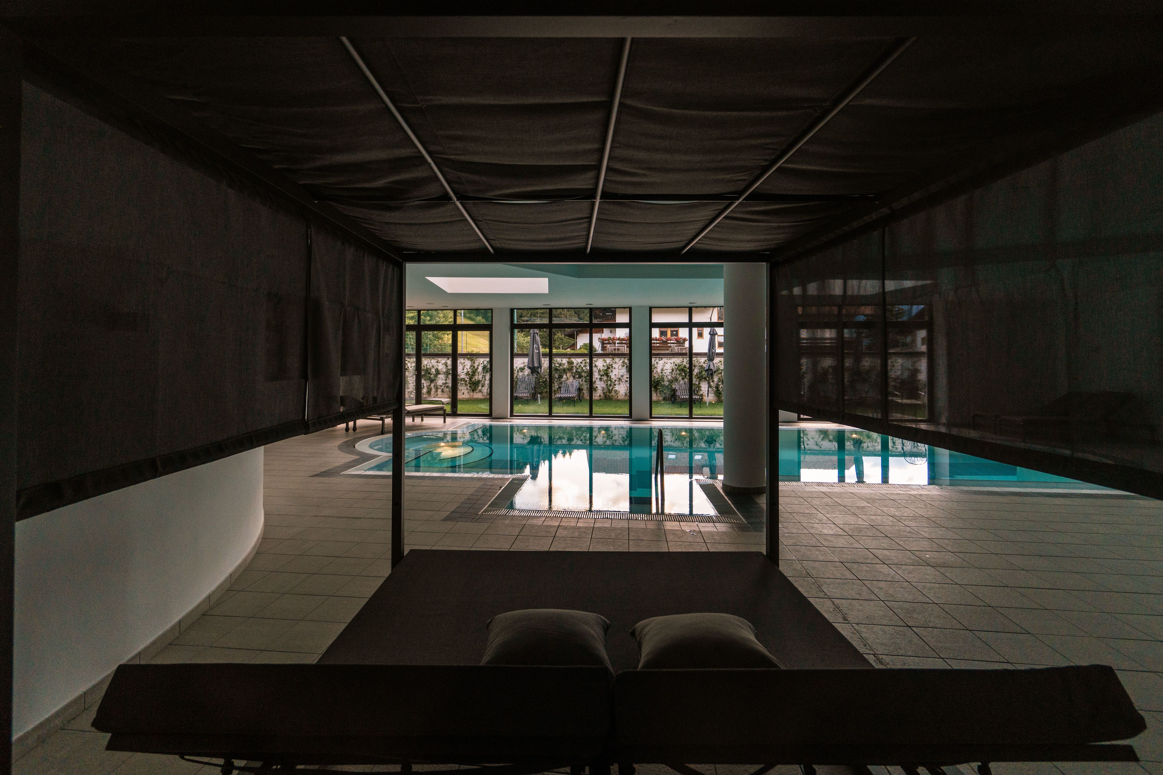 Zona junto a la piscina con vista a ella y un patio con mesa y sillas.