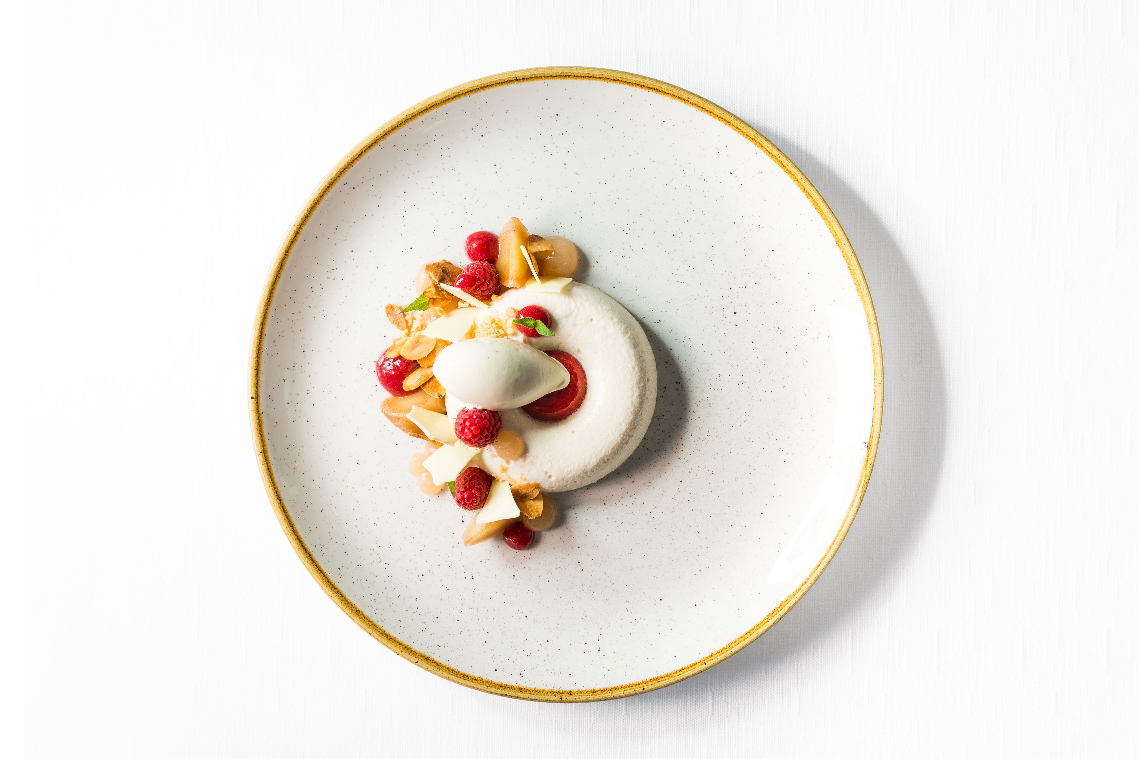 A dessert on a white plate with a gold rim.