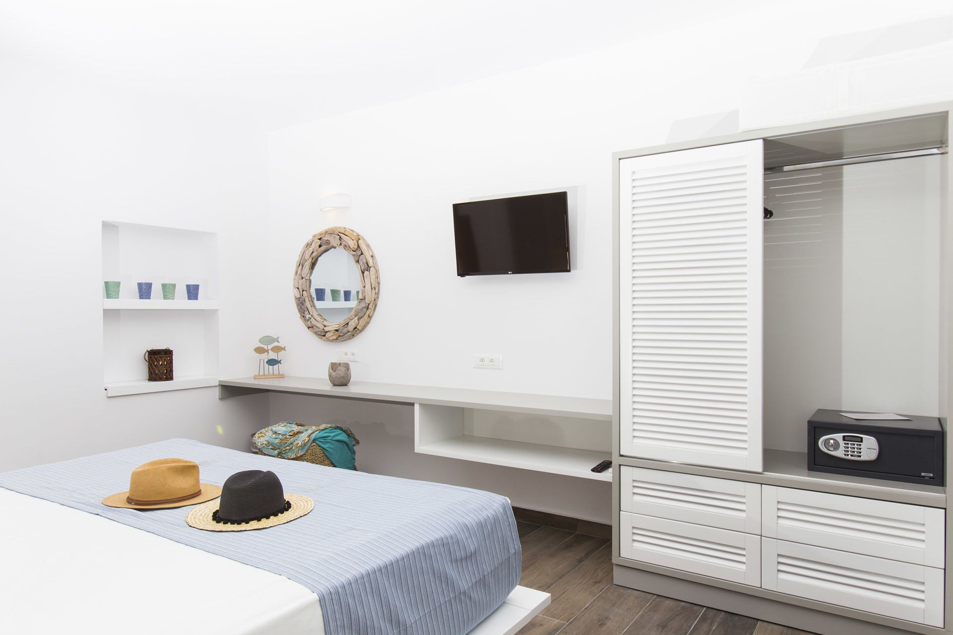A bedroom with a bed, a TV, a wardrobe, and a shelf with decorative items.