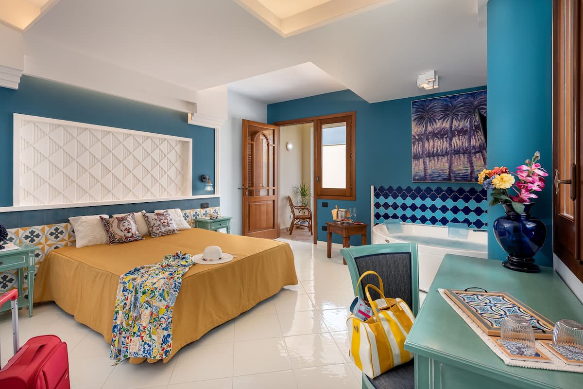 Un dormitorio amplio con una cama grande, un escritorio con un florero y vistas al exterior.