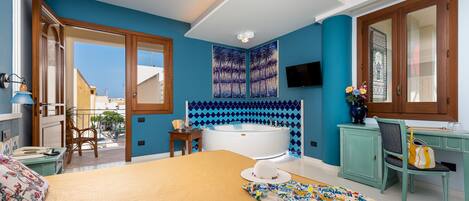 A bedroom with a large bed, a bathtub, a desk, and a chair.