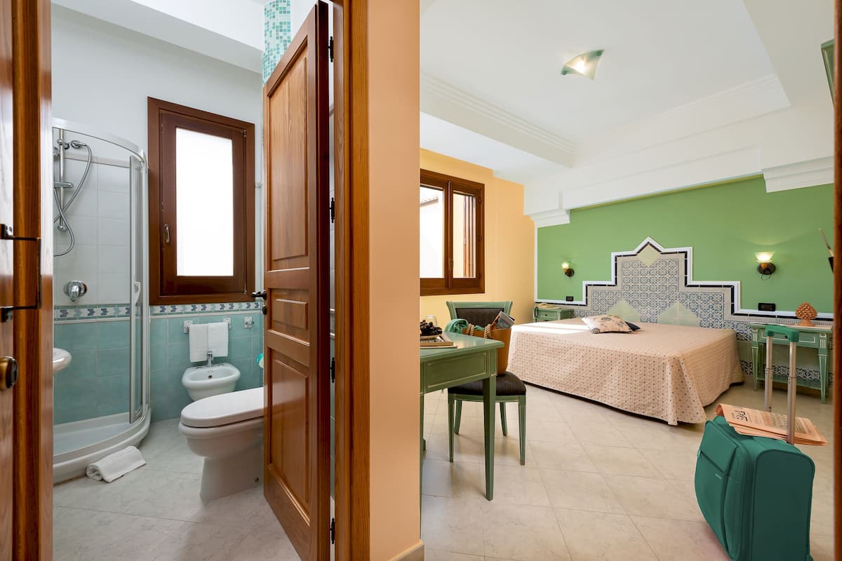 Un baño con ducha, inodoro y lavamanos, y un dormitorio con cama, escritorio y silla.