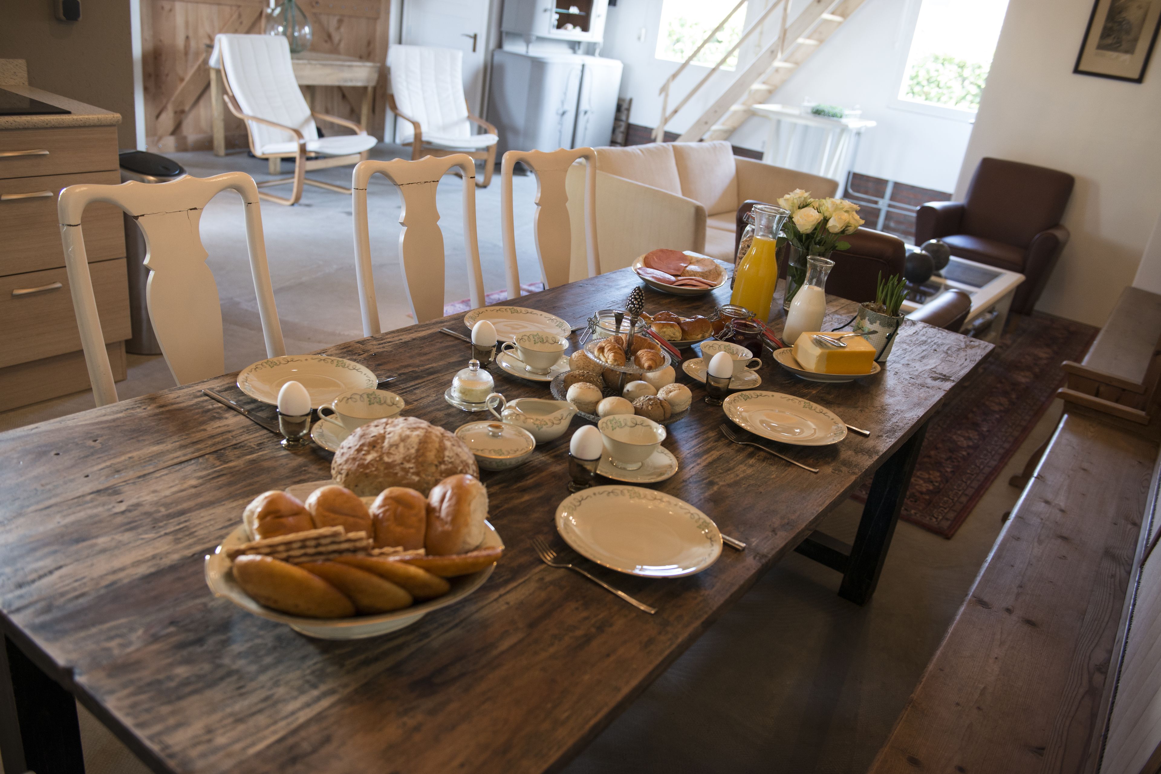 A dining table set with breakfast items, including pastries, eggs, and juice.