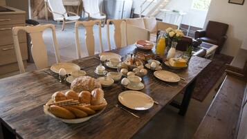 A dining table set with breakfast items, including pastries, eggs, and juice.
