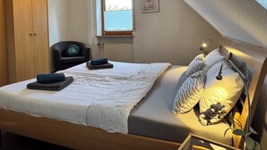 Ein Schlafzimmer mit einem Bett, einem Sessel, einem Fenster und einem Kleiderschrank.