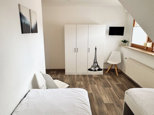 A bedroom with a bed, a wardrobe, a desk, and a chair. - Ferienwohnung Weiher nähe Nürnberg Messe (Schwanstetten)