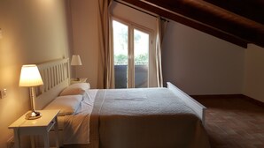 Un dormitorio con una cama, una mesita de noche, una lámpara y una ventana con cortinas.