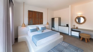 A bedroom with a bed, bedside tables, a wardrobe, a mirror, and a hanging light fixture. - Lindos Portes Suites - Adults Only (Rhodes)