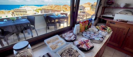 Un bufé de desayuno con diferentes alimentos y vistas al mar y edificios.