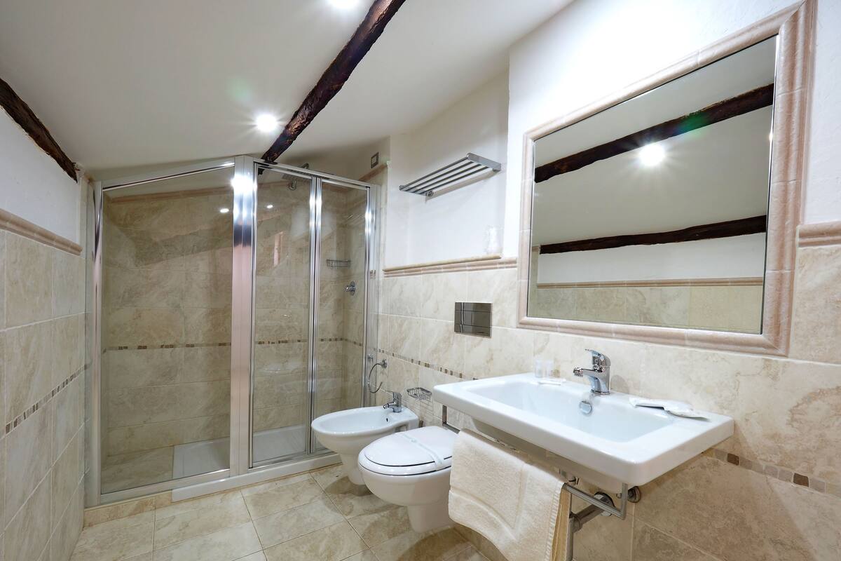 Un baño con ducha envuelta en vidrio, inodoro, lavabo y espejo.