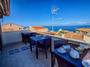 Une terrasse avec des tables et des chaises, une vue sur la mer et une antenne parabolique.
