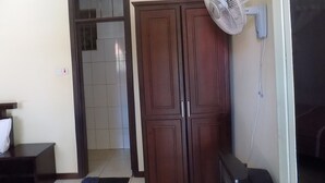 A room with a wardrobe, a fan, and a door leading to another room. - Etana Motel (Kampala)